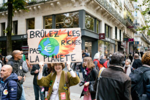 Une manifestante avec une pancarte avec le slogan "brûlez les riches, pas la planète". Manifestation intersyndicale pour l'augmentation des salaires. Photographie de Martin Noda / Hans Lucas. France, Paris, 2022-09-29.